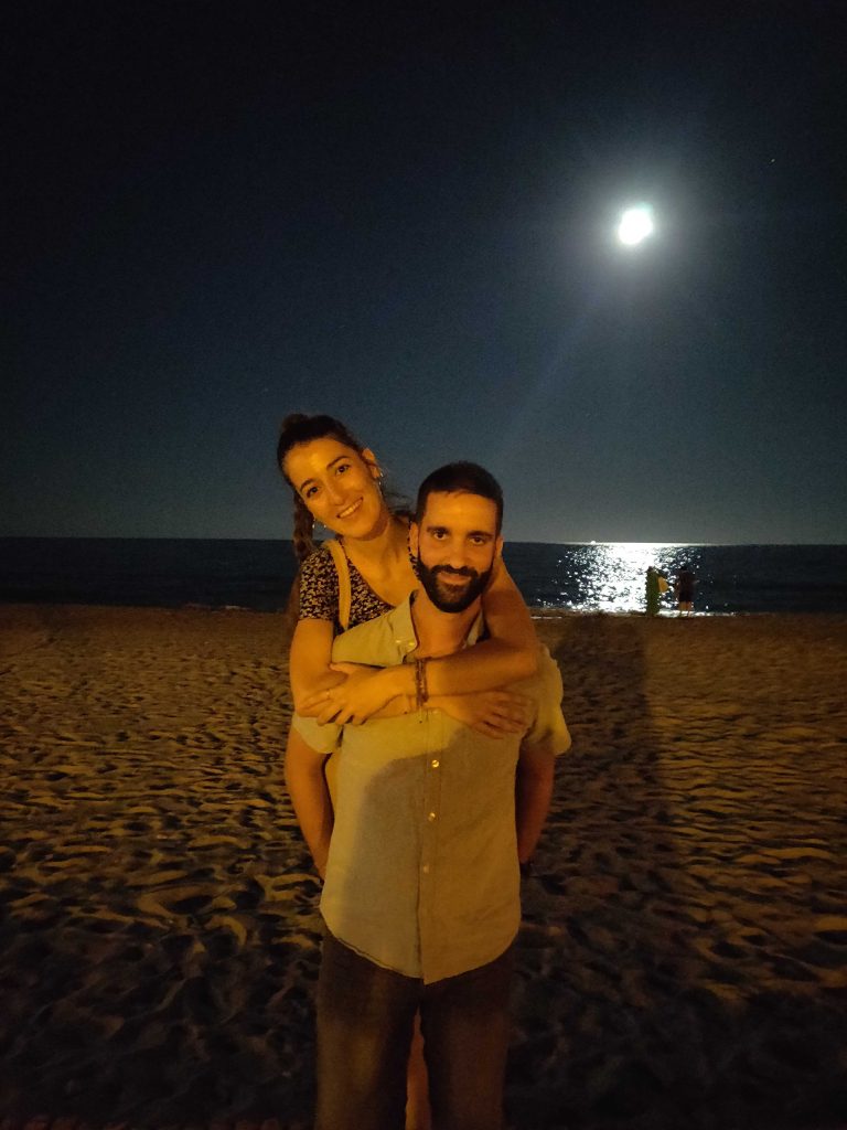 Foto en pareja de la playa del Arenal de noche con la luna de fondo 