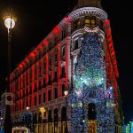 bright facade with lights of Christmas decorations in Madrid at night with people and cars in a main street.